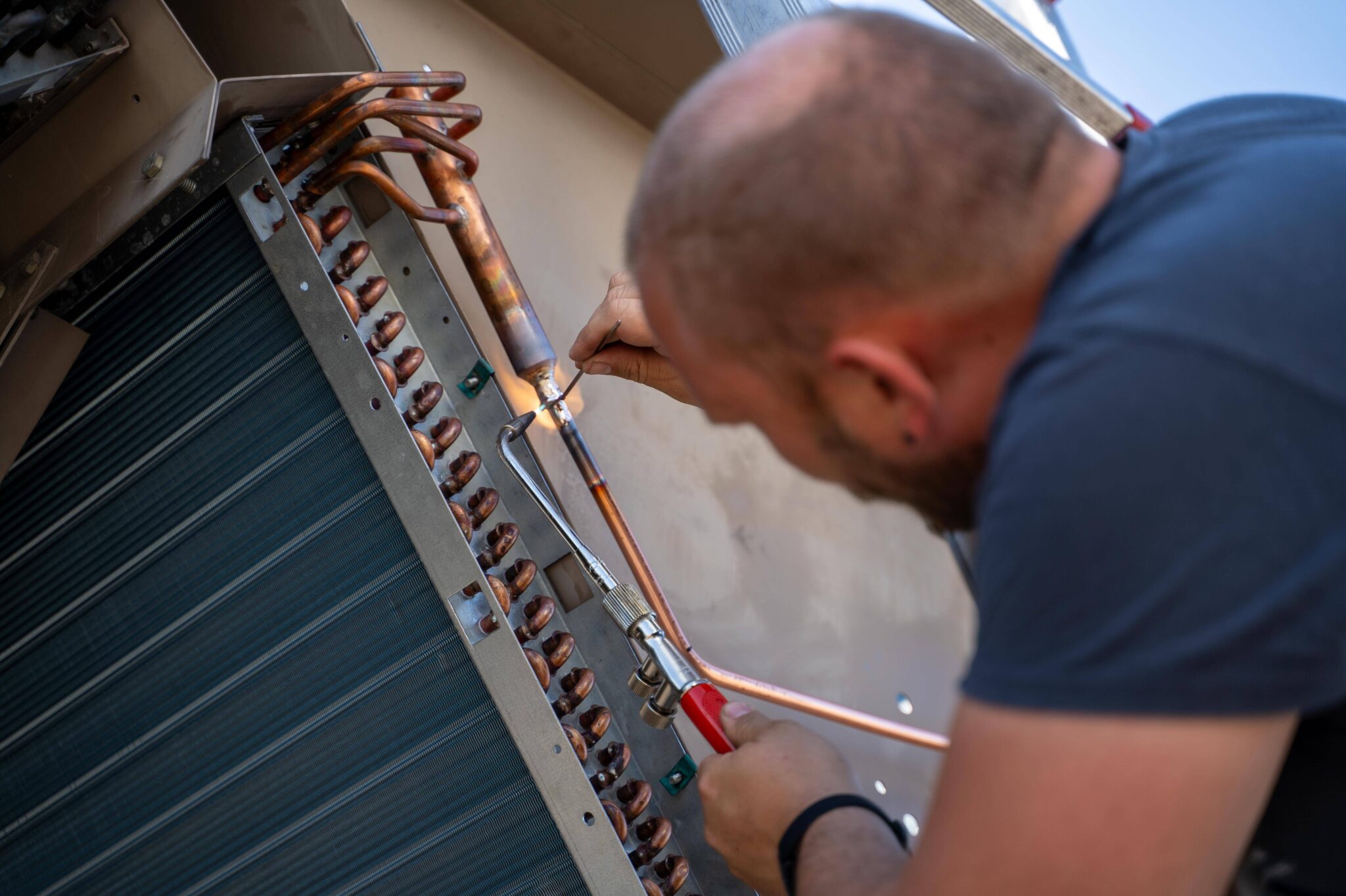 Kältetechniker lötet Kupferrohre an einer Industriekälteanlage für optimale Kühlleistung